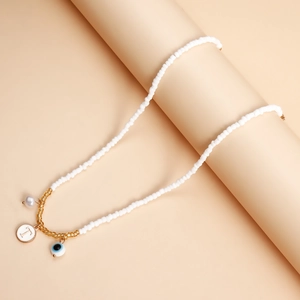 Detail of bohemian white beaded necklace with Evil Eye and T-letter charms