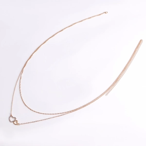 Détail d'une chaîne de taille dorée à double rang avec pendentifs en cœur serti et poli