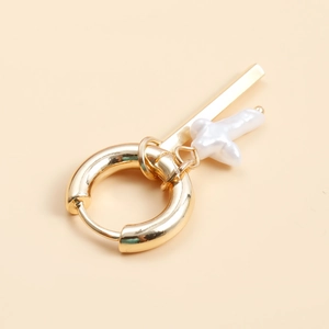 Detailed close-up of gold geometric hoop earring with baroque pearl and star pendant charms