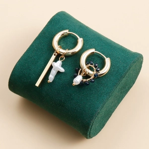 Detailed shot of asymmetric gold earrings with baroque pearl and blue crystal beads