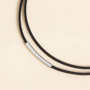 Detailed macro shot of a black velvet cord necklace with a polished silver curved tube