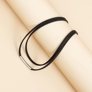 Detail of a minimalist black velvet rope necklace wrapped around a cylinder display