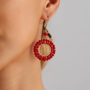 Red crystal beaded hoop earrings with gold wire weaving shown on a female model