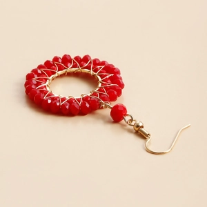Macro shot of handmade red crystal beaded hoop earrings with gold woven wire detail