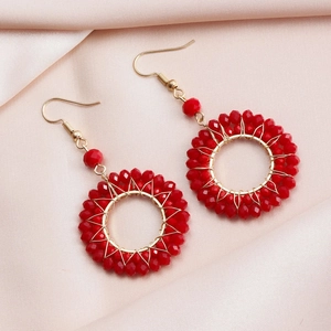 Elegant woven red crystal hoop earrings with golden ear hooks on a pink silk background