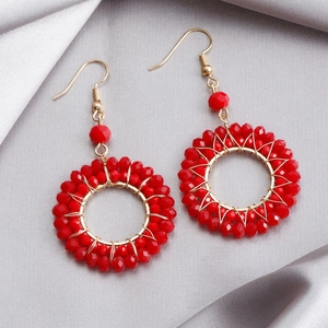 Detail of red faceted crystal bead woven earrings with golden wire and hook