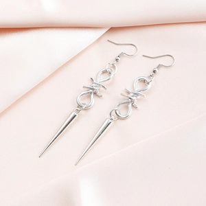 Detail of silver gothic earrings with thorn knot and long metallic spike pendants