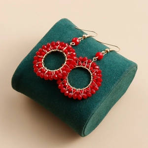 Close-up of bohemian round gold hoop earrings with faceted red crystal beads on velvet