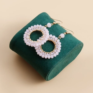 Detail of handmade gold woven hoop earrings featuring soft pink faceted crystal beads