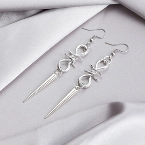 Detail view of Gothic silver thorn wire earrings with long spiked rivet tassels on silk