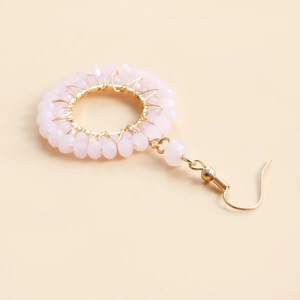Detailed macro view of pink crystal beads woven on gold circle earrings for women