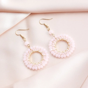 Close-up of pink beaded hoop earrings with gold wire weaving and fishhook style backs