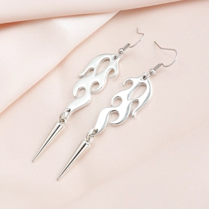 Macro shot of silver gothic flame earrings with long spike pendants on pink silk