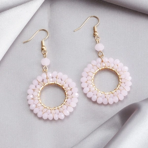 Detail of pink crystal beaded hoop earrings on silk background with gold metal wire weave