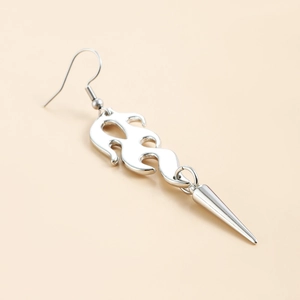 Close-up of gothic silver flame earring with long tassel spike pendant on beige background