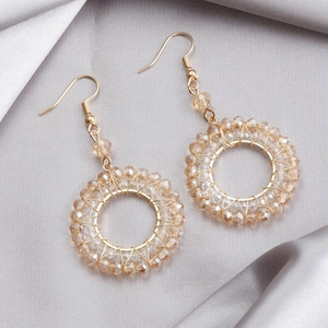 Detailed close-up of champagne crystal beaded hoop earrings on elegant grey silk fabric