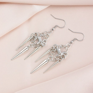 Detail of silver gothic tassel earrings with metal spikes on pink silk backdrop