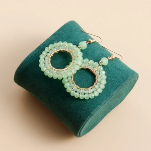 Close-up of light green crystal beads woven on a circular golden hoop earring