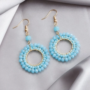 Detailed macro view of blue crystal woven hoop earrings on elegant silver satin fabric