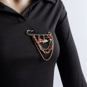 Macro shot of gold-plated Christmas brooch with NOEL charms and chains on black fabric