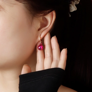 Close-up of rose red Christmas bell earrings with heart cutout on a female model