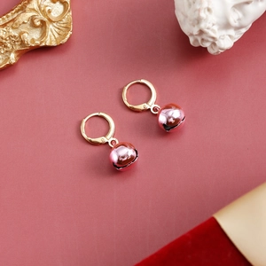 Detailed view of pink metallic bell earrings on an artistic festive background