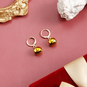 Detailed macro view of golden bell pendant earrings on elegant velvet gift box