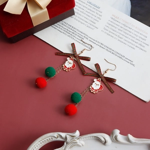 Dettaglio di orecchini natalizi con fiocchi, ciondoli Babbo Natale e palline di peluche