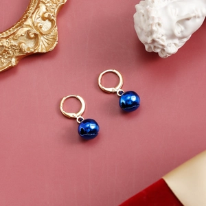 Detailed macro view of golden hoop earrings featuring vibrant blue Christmas bell pendants