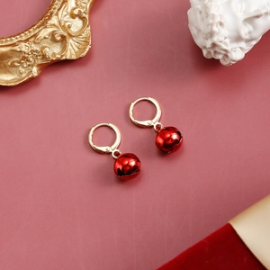 Detail of red metal bell pendants hanging from golden hoops with a festive backdrop