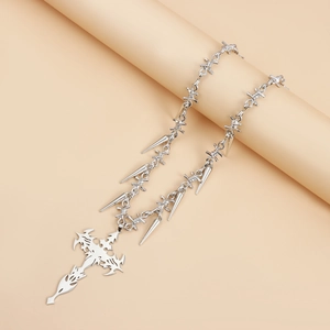 Detail shot of silver punk cross necklace with metallic spikes and barbed wire chain