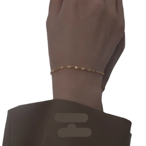 Minimalist gold thin lip chain bracelet for women worn with a dark suit jacket