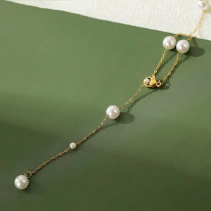 Detailed close-up of golden stainless steel chain with lustrous pearls and lobster clasp