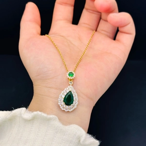 Luxurious gold necklace with pear-shaped emerald green stone and white zircon halo