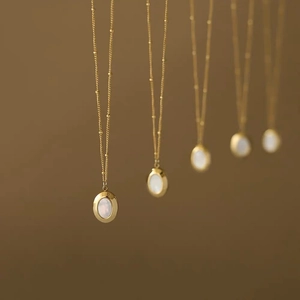 Detail of vintage gold bead chain necklace with oval white mother of pearl pendant
