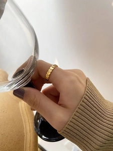 Exquisiter goldener geometrischer Schichtring am Finger hält ein edles Glas