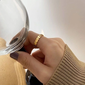 Minimalistischer goldener Ring mit geometrischen Scheiben an Hand mit Weinglas