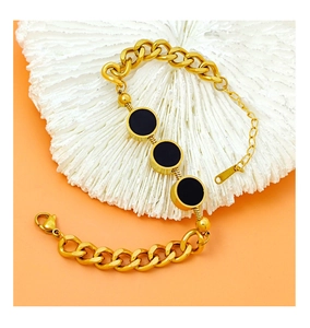 Detail eines klobigen Goldketten-Armbands mit schwarzen Emaille-Anhängern auf weiß