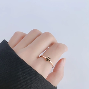 Minimalist 18k rose gold daisy ring with black flower detail worn by a model