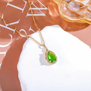 Dettaglio di una collana placcata oro con gemma verde a goccia e alone di zirconi bianchi