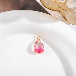 Détail d'un pendentif en cristal rose en forme de goutte avec placage or sur plat blanc