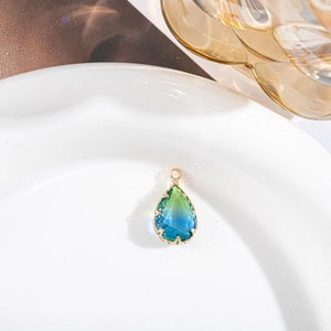 Vue macro d'un pendentif en cristal doré en forme de poire avec dégradé vert et bleu