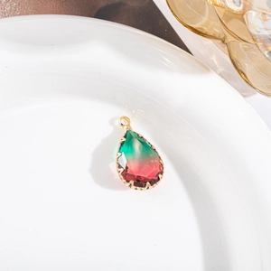 Detail van een druppelvormige kristallen hanger met groen-roze verloop in gouden zetting