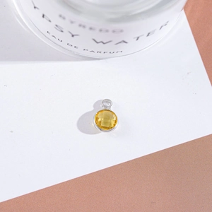 Macro shot of silver-framed round yellow crystal pendant with multi-faceted gemstone surface