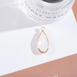 Macro shot of gold-plated pear-cut milky white crystal drop pendant on white display