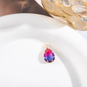 Détail d'un pendentif goutte en cristal dégradé avec sertissage couronne dorée sur plat