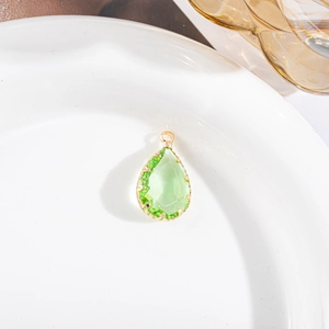 Detail van een groene kristallen druppelhanger met vergulde klauwzetting voor sieraden