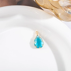 Détail macro du pendentif goutte en cristal bleu avec sertissage à griffes plaqué or