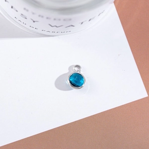 Macro detail of a round blue faceted crystal pendant with silver plated metal bezel setting