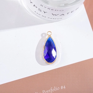 Detail of gold-plated teardrop pendant with a faceted violet crystal and hanging loop